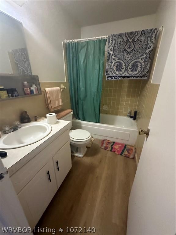 full bathroom with hardwood / wood-style floors, shower / bath combination with curtain, toilet, and vanity