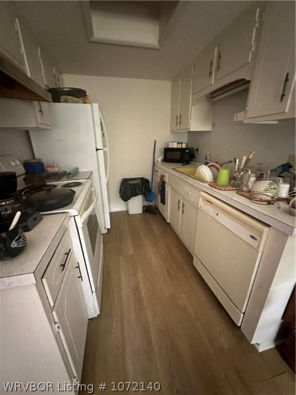 kitchen with white cabinets, dark hardwood / wood-style floors, white appliances, and sink