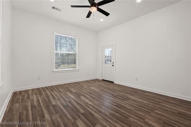 spare room featuring dark wood-type flooring, visible vents, and a healthy amount of sunlight