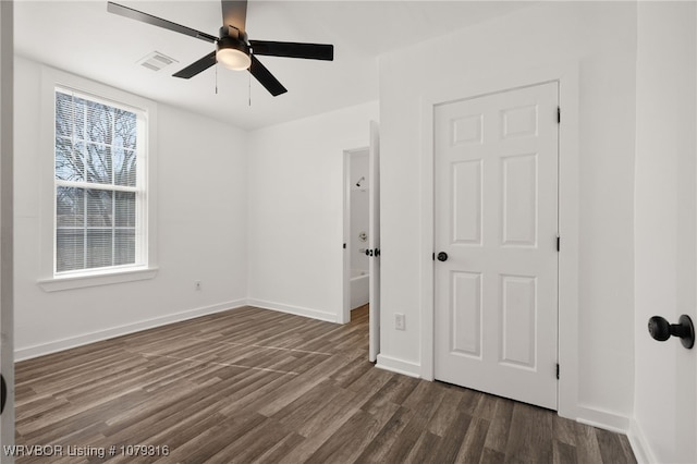 unfurnished bedroom with dark wood-style floors, visible vents, ceiling fan, and baseboards