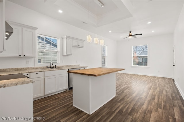 kitchen with butcher block counters, dark wood-type flooring, a sink, white cabinets, and a raised ceiling