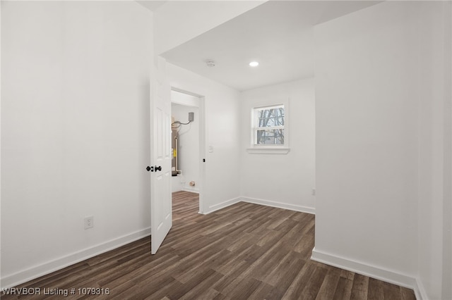 empty room with dark wood-type flooring and baseboards