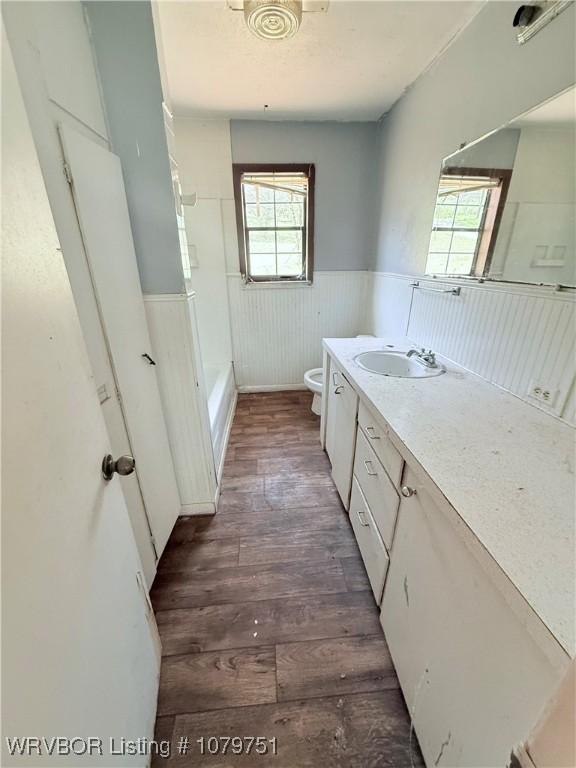 full bathroom with vanity, wood finished floors, wainscoting, shower / washtub combination, and toilet