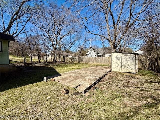 view of yard with an outbuilding, fence, a shed, and a patio area