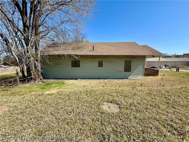 rear view of property featuring a lawn and roof with shingles