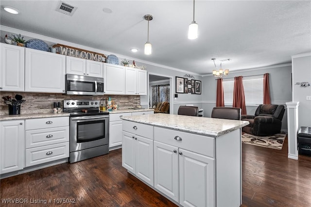 kitchen with tasteful backsplash, white cabinetry, hanging light fixtures, and appliances with stainless steel finishes