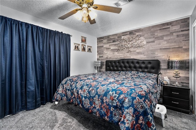 carpeted bedroom with a textured ceiling, ceiling fan, and wood walls