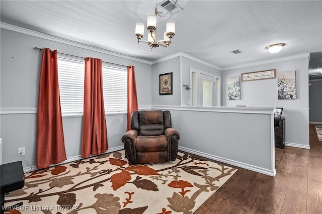 living area featuring a textured ceiling, a chandelier, dark hardwood / wood-style floors, and ornamental molding