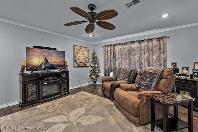 living room featuring hardwood / wood-style floors, ceiling fan, ornamental molding, and a textured ceiling