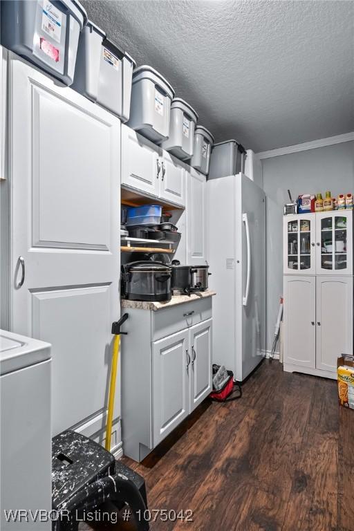 kitchen with white cabinetry, dark wood-type flooring, white refrigerator, a textured ceiling, and washer / dryer