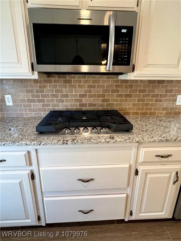 2205 Crosshill Rd, Fort Smith, AR 72908 - kitchen view of stainless steel appliances, white cabinets, backsplash, and light stone countertops