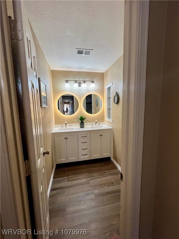2205 Crosshill Rd, Fort Smith, AR 72908 - bathroom featuring wood finish floors, a textured ceiling, double vanity, and baseboards