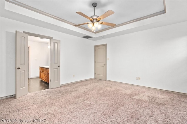 unfurnished bedroom featuring carpet flooring, a tray ceiling, ceiling fan, and ornamental molding