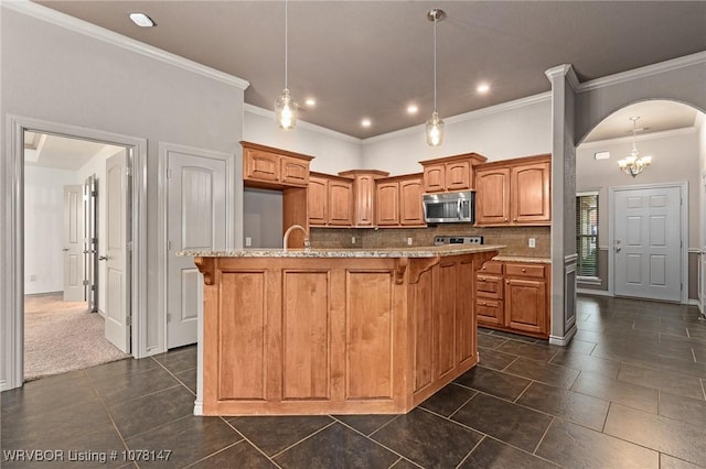 kitchen with a center island with sink, decorative backsplash, ornamental molding, and hanging light fixtures