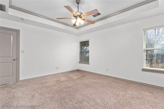 carpeted spare room featuring a tray ceiling, crown molding, and ceiling fan