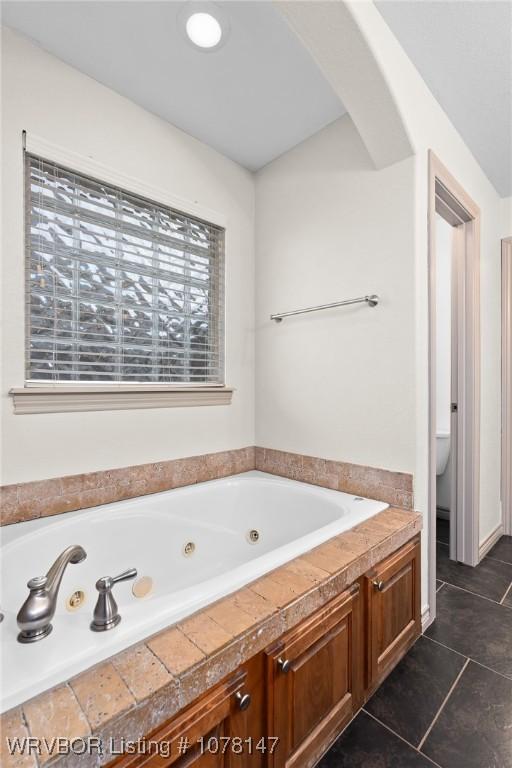 bathroom with tile patterned floors, toilet, and tiled tub