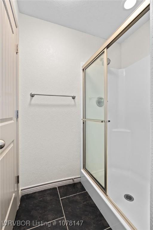 bathroom with a shower with door and tile patterned flooring