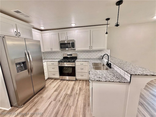 kitchen featuring white cabinets, sink, decorative light fixtures, kitchen peninsula, and stainless steel appliances