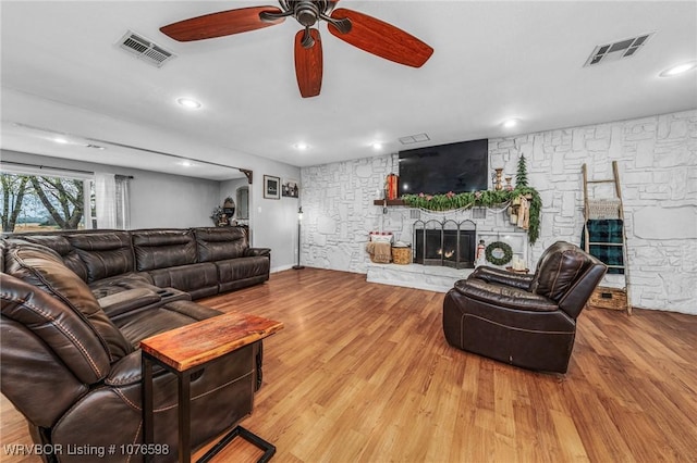 living room featuring ceiling fan, light hardwood / wood-style floors, and a fireplace