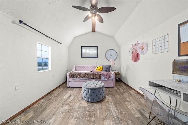 sitting room with ceiling fan, hardwood / wood-style floors, and lofted ceiling