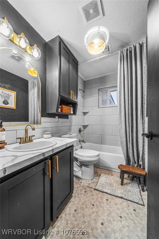 full bathroom featuring tasteful backsplash, shower / bath combination with curtain, a textured ceiling, toilet, and vanity