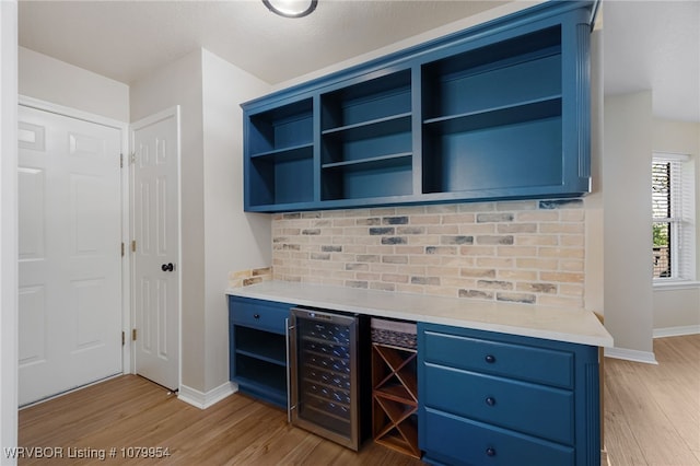 bar with wine cooler, light wood finished floors, baseboards, and tasteful backsplash