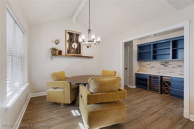 dining room with lofted ceiling with beams, wood finished floors, wine cooler, and a healthy amount of sunlight