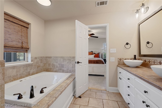 ensuite bathroom featuring connected bathroom, a sink, double vanity, visible vents, and a whirlpool tub