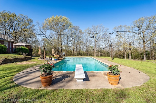 pool featuring a lawn, a diving board, and a patio