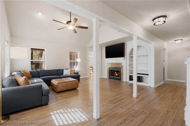 living area featuring vaulted ceiling, ceiling fan, light wood-style floors, and a fireplace