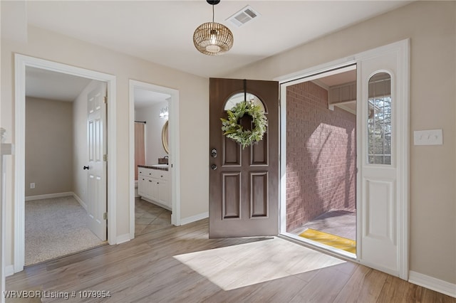 foyer with baseboards, visible vents, and light wood-style flooring