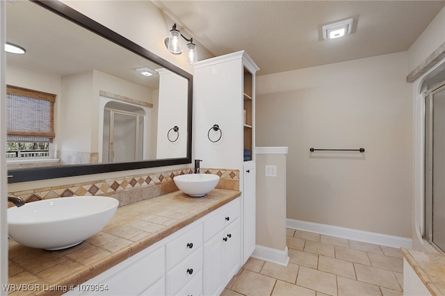 bathroom with double vanity, a sink, a shower stall, and tile patterned floors