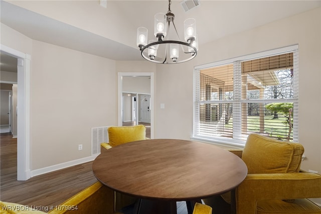 dining area featuring wood finished floors, visible vents, a chandelier, and baseboards
