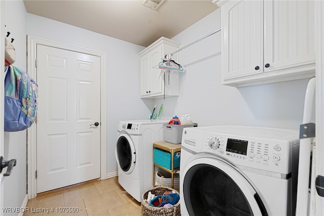 laundry room featuring cabinets, light tile patterned floors, and washing machine and clothes dryer