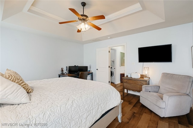 bedroom with washer / clothes dryer, a raised ceiling, ceiling fan, and hardwood / wood-style flooring