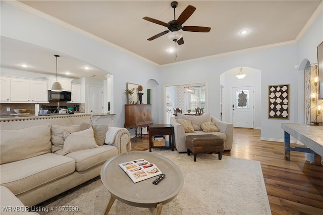 living room featuring ceiling fan, crown molding, and light hardwood / wood-style flooring