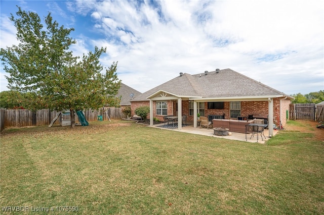 rear view of house with a playground, a patio, a yard, and an outdoor living space with a fire pit