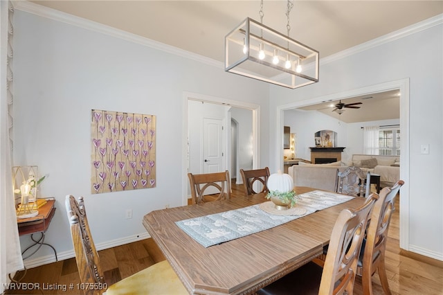 dining room featuring hardwood / wood-style floors, ceiling fan with notable chandelier, and crown molding