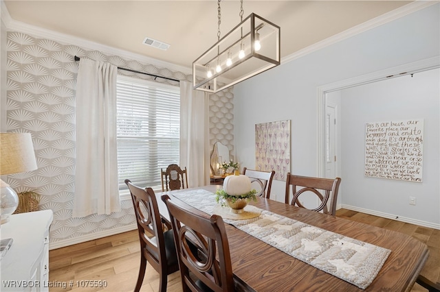 dining room with crown molding, a notable chandelier, and light wood-type flooring