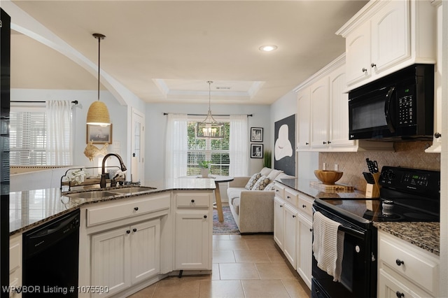 kitchen featuring black appliances, decorative light fixtures, sink, and a tray ceiling