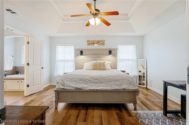 bedroom featuring ceiling fan, a raised ceiling, multiple windows, and light hardwood / wood-style flooring