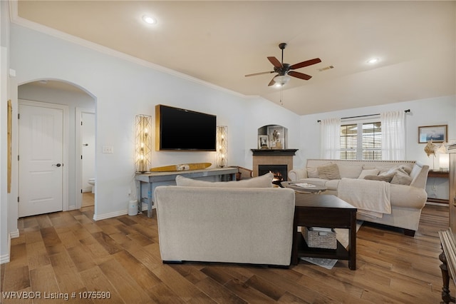 living room with wood-type flooring, ornamental molding, ceiling fan, and lofted ceiling