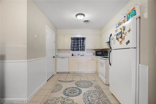 kitchen featuring white cabinetry, light tile patterned flooring, white appliances, and a textured ceiling