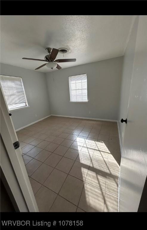 tiled spare room with a textured ceiling and ceiling fan