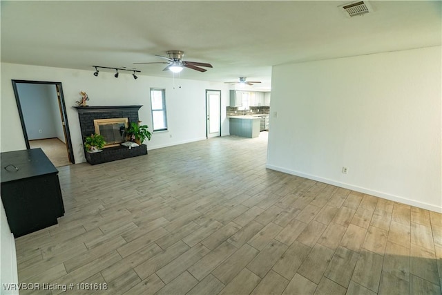 8617 S 15th St, Fort Smith, AR 72908 - unfurnished living room featuring ceiling fan, light wood-style floors, track lighting, and a fireplace