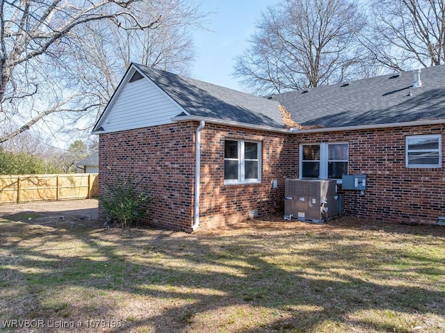 view of home's exterior with central AC, fence, a lawn, and brick siding