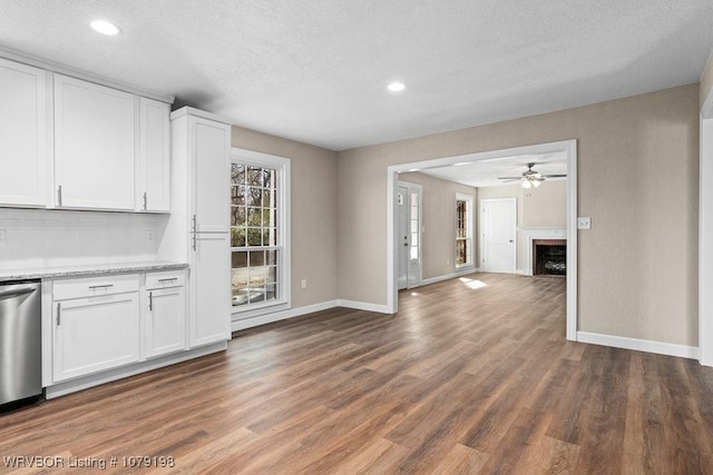 kitchen with a fireplace, white cabinets, open floor plan, dark wood-style floors, and dishwasher