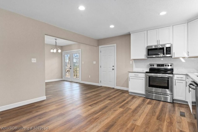 kitchen featuring white cabinets, dark wood finished floors, stainless steel appliances, and backsplash