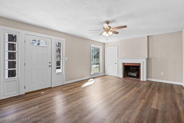 unfurnished living room featuring dark wood-style floors, a fireplace, a textured ceiling, and baseboards