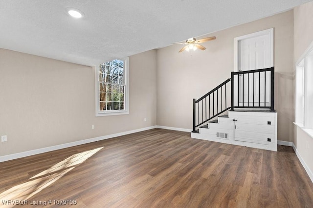 unfurnished living room with a ceiling fan, baseboards, and dark wood-type flooring